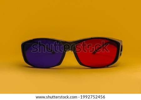 3D Red and cyan cinema eyeglasses isolated on orange background. 3D movie glasses stock images.