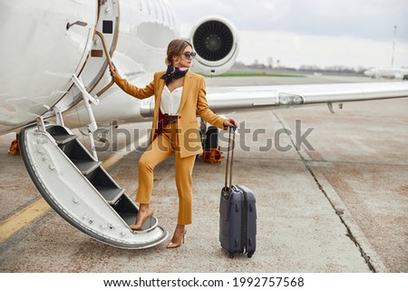 Businesswoman going up on ladder of airplane Royalty-Free Stock Photo #1992757568