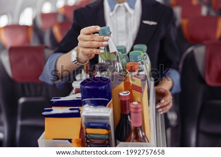 Stewardess take water bottle from trolley cart Royalty-Free Stock Photo #1992757658