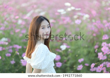 Beautiful young woman with white dress on pink cosmos flowers background