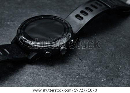 A modern carbon fiber smartwatch on a black board