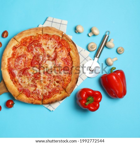 Tasty pizza and ingredients on blue background