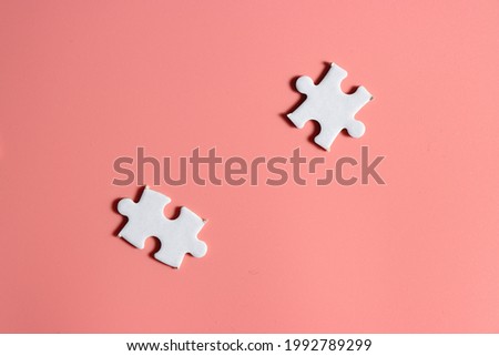 two white jigsaw puzzle pieces isolated on pink background 
