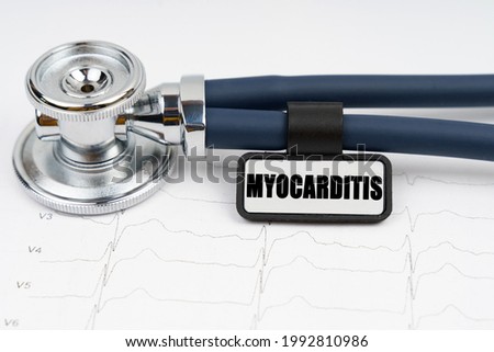 Medicine and health concept. On the cardiogram is a stethoscope and a plate with the inscription - Myocarditis Royalty-Free Stock Photo #1992810986