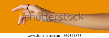 Womans hand with jewelry accessories over orange background. Beauty fashion creative layout in minimal slyle Royalty-Free Stock Photo #1992811673
