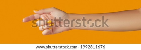 Womans hand with jewelry accessories over orange background. Beauty fashion creative layout in minimal slyle Royalty-Free Stock Photo #1992811676