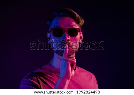 Portrait of attractive mysterious guy showing shh sign keep silence isolated over dark neon violet color background Royalty-Free Stock Photo #1992824498