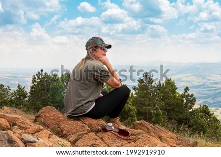 Tourist girl hiker, photographer resting at the top of the mountain and enjoying amazing landscape view of mountains and beautiful sky