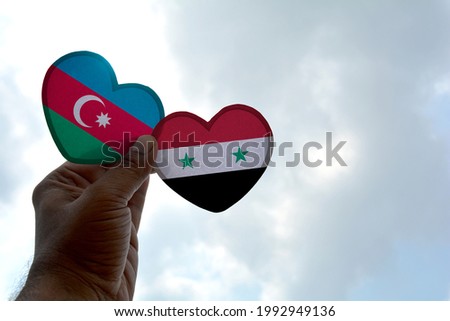 Hand holds a heart Shape Azerbaijan and Syria flag, love between two countries