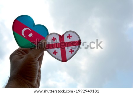 Hand holds a heart Shape Azerbaijan and Georgia flag, love between two countries