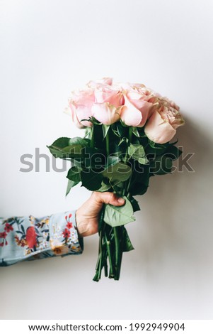 Woman holding a bouquet of flowers by the wall