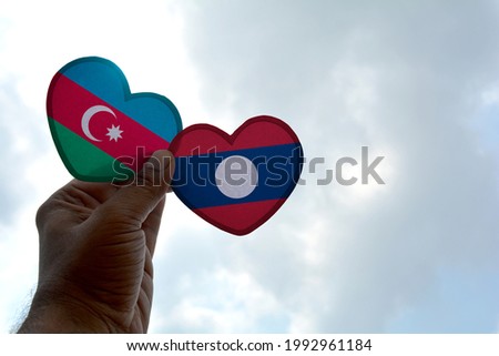 Hand holds a heart Shape Azerbaijan and Laos flag, love between two countries