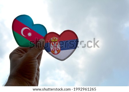 Hand holds a heart Shape Azerbaijan and Serbia flag, love between two countries