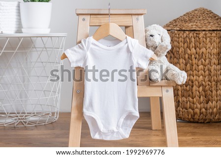 White baby short sleeve bodysuit mockup for presentation cute sublimation designs. Minimalistic photos of romper for toddlers in scandinavian interior with minimalistic decoration Royalty-Free Stock Photo #1992969776