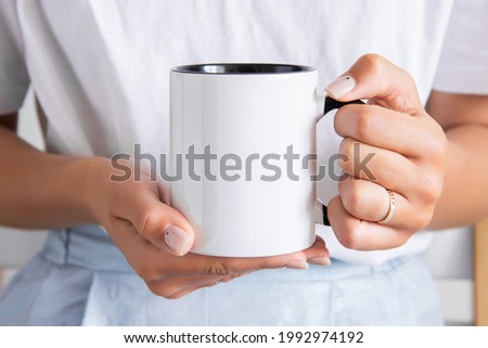 Two tone black and white mug mockup for presentation sublimation designs. Stock photos of white coffee mug in the female hands  for designers Royalty-Free Stock Photo #1992974192