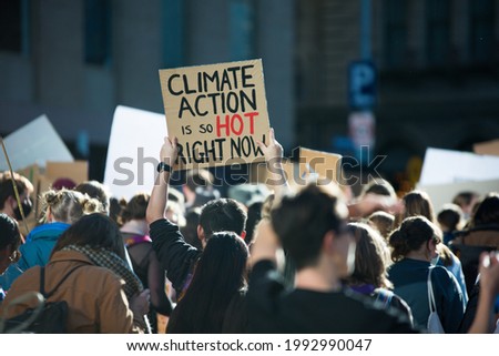 "Climate Action is so hot right now" text written on a sign at student climate change protest in Melbourne Australia. Group of protesters marching down street against global warming. Focus on sign. Royalty-Free Stock Photo #1992990047