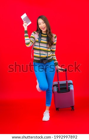 Portrait beautiful young asian woman with luggage and boarding pass on red background