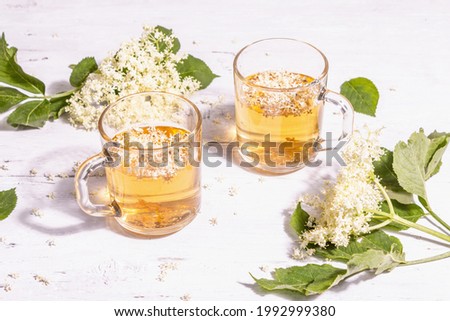 Elderberry flower tea. Refreshing summer drink, healthy lifestyle concept. Trendy hard light, dark shadow. Old white wooden boards background, close up