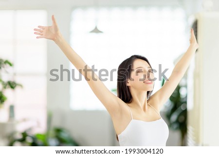 Young woman taking  deep breath  in living room at morning Royalty-Free Stock Photo #1993004120