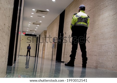 A low-angle shot of security guards patrolling inside a commercial building 