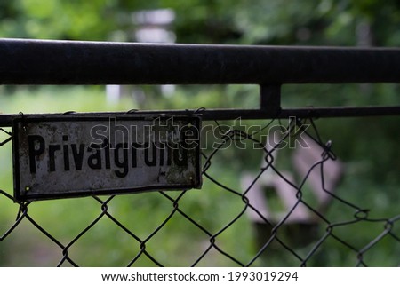 German sign on a fence saying private property - bench and grass in the bac´kground