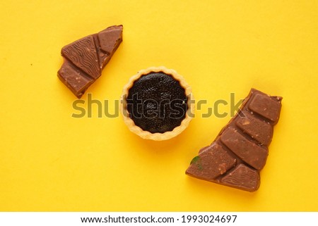 A picture of chocolate tart and bar on yellow background. Food prepared for dessert.
