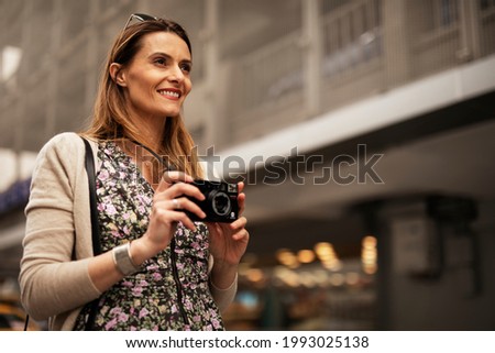 Attractive tourist with a camera. Beautiful woman with camera taking photos of beautiful location.	