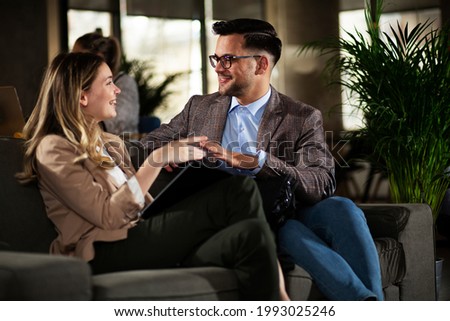 Colleagues talking in the office. Businesswoman and businessman laughing in the office