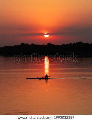 silhouette picture  of a man rowing on the lake doing a sunset