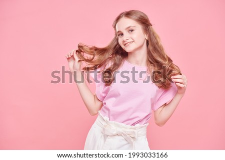 Portrait of a cute teenage girl smiling at camera on a pink background. Youth fashion.