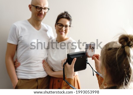 Girl made a photo of her parents using  instant camera at home