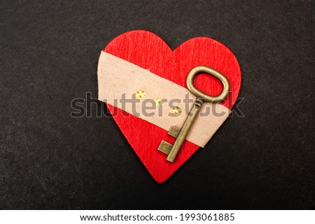 A conceptual image of a key and hurt heart with a plaster in the black background