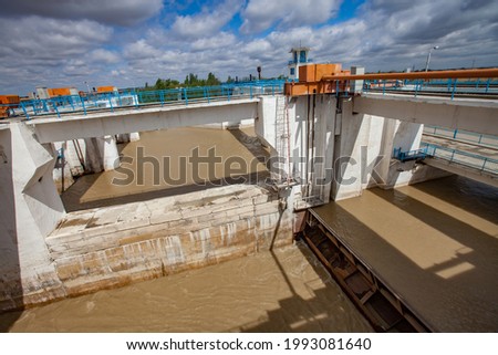 Shardara river dam and bridge. Water shutter down. Orange speed changer. Blue sky, clouds. Kazaly city, Kyzylorda region, Kazakhstan.