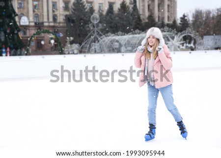 Happy woman skating along ice rink outdoors. Space for text