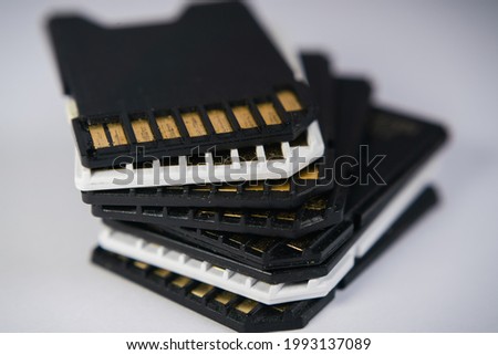 Black and white memory cards are stacked on top of each other on a uniform background. Memory for electronic gadgets