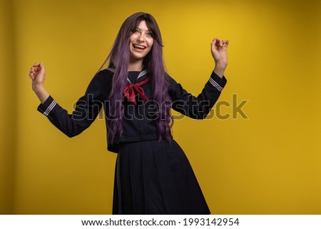 Beautiful young brunette girl in the uniform of a Japanese schoolgirl on a yellow background