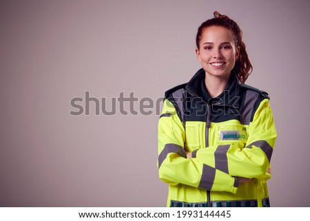 Studio Portrait Of Smiling Young Female Paramedic Against Plain Background Royalty-Free Stock Photo #1993144445