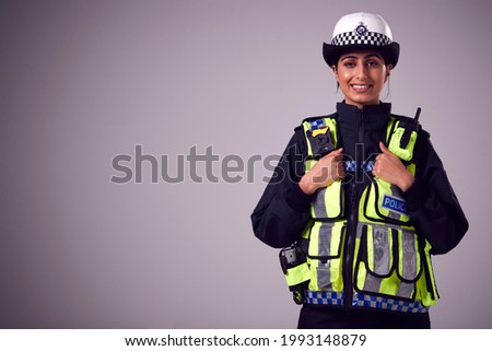 Studio Portrait Of Smiling Young Female Police Officer Against Plain Background Royalty-Free Stock Photo #1993148879