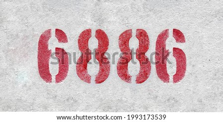 Red Number 6886 on the white wall. Spray paint. Number six thousand eight hundred and eighty six.