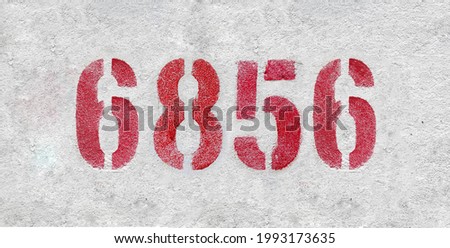 Red Number 6856 on the white wall. Spray paint. Number six thousand eight hundred fifty six.