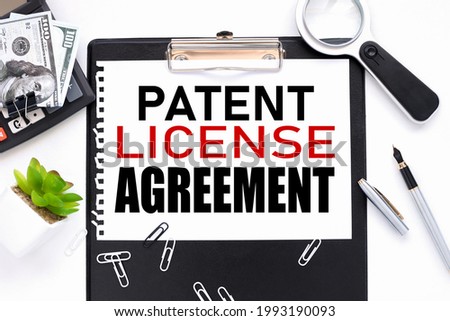 patent licence agreement. text on a white sheet of paper near a magnifying glass m flowerpot in a pot