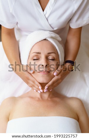 Face massage. Close-up of adult woman getting spa massage treatment at beauty spa salon. Spa skin and body care. Facial beauty treatment. Cosmetology. Royalty-Free Stock Photo #1993225757