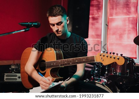Songwriter thinking and writing notes, lyrics on sheets at studio. Concept for musician creative, artist composer in work process Royalty-Free Stock Photo #1993231877