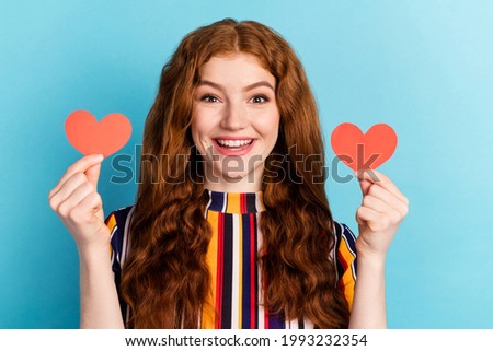 Photo of impressed red hairdo young lady hold hearts wear colorful shirt isolated on blue color background