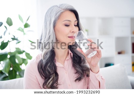 Photo of charming pretty positive old woman drink water glass thirsty indoors inside house home apartment
