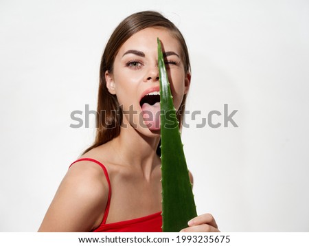 woman with clean hair and fair skin licks an aloe leaf on a light background