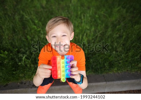 the child squats, looks up and laughs merrily, holding an anti-stress silicone toy balls that burst