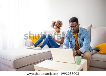 Millennial generation father working from home with small children while in quarantine isolation during the Covid-19 health crisis. Little girl on tablet computer. Horizontal indoors