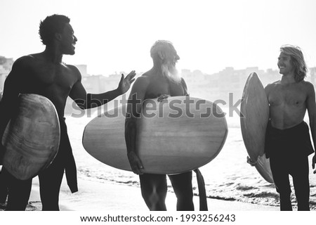 Multi generational surfer men having fun on the beach - Focus on bodies silhouettes - Black and white editing