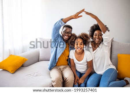 Happy family forming house roof with their hands at home. Insurance concept. Concept of housing and relocation. happy family mother father and kids with roof at home Royalty-Free Stock Photo #1993257401